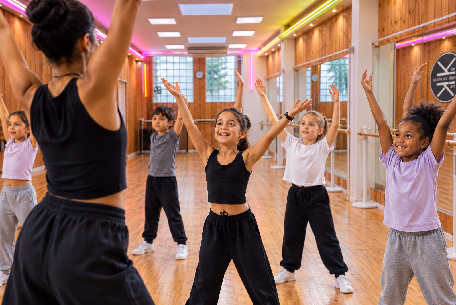 Éveil 4-5 ans : des enfants lèvent les bras en imitant leur professeure, dans la salle 1 de Gambetta.