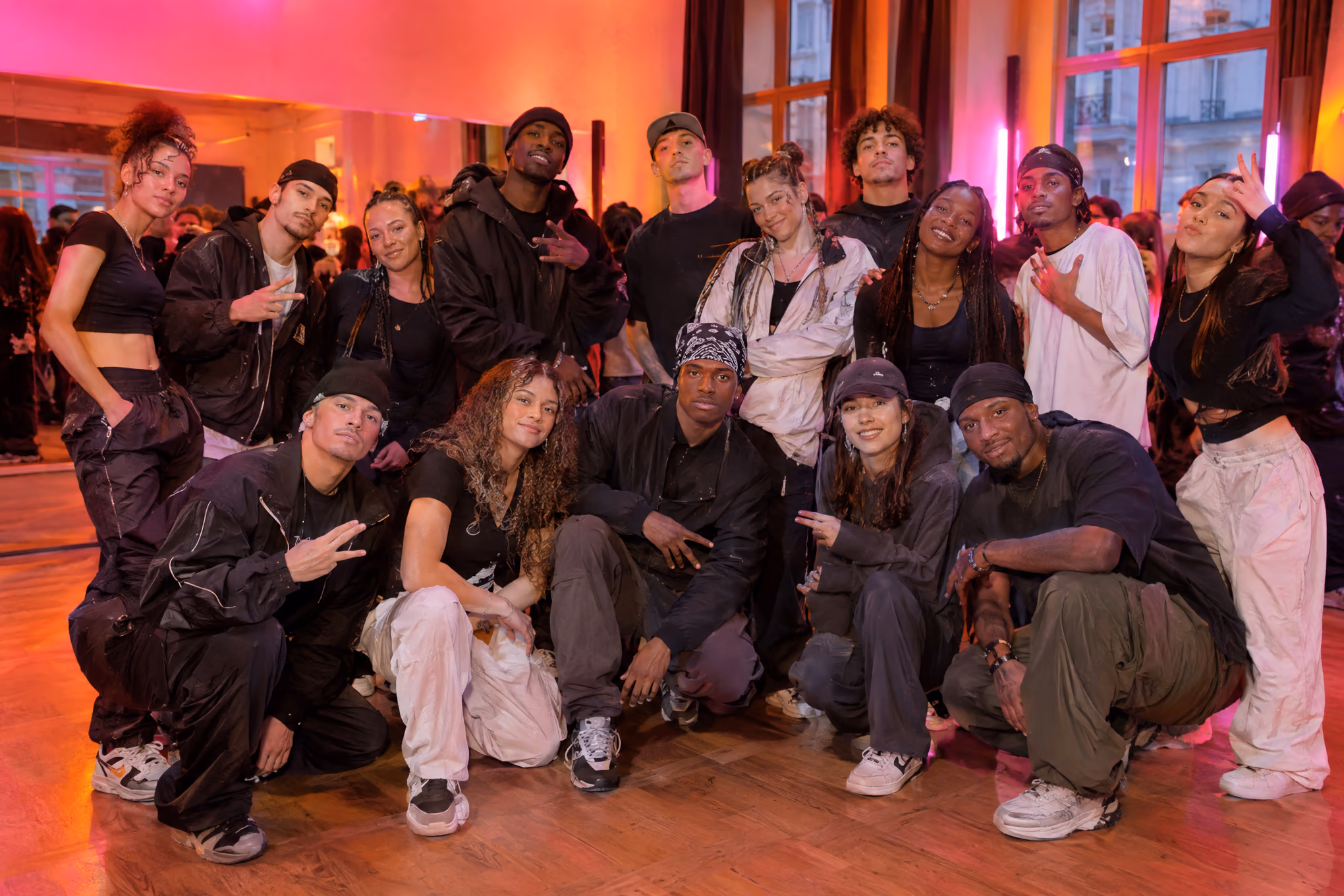 Photo de groupe de danseurs hip hop, lumières roses et orange.