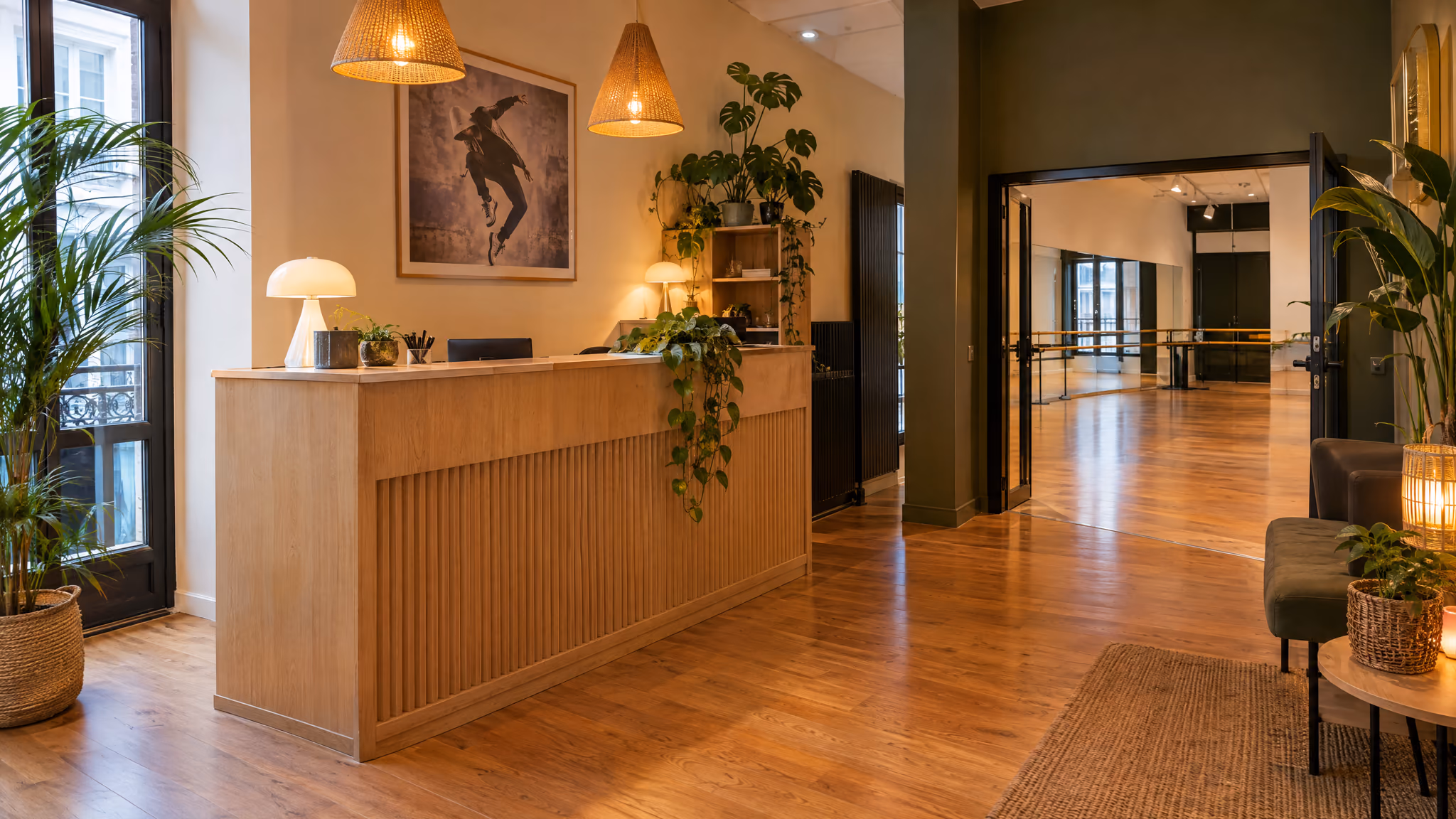 Accueil du studio Gambetta : comptoir en bois clair, plantes vertes, lampes chaudes, tableau au mur.