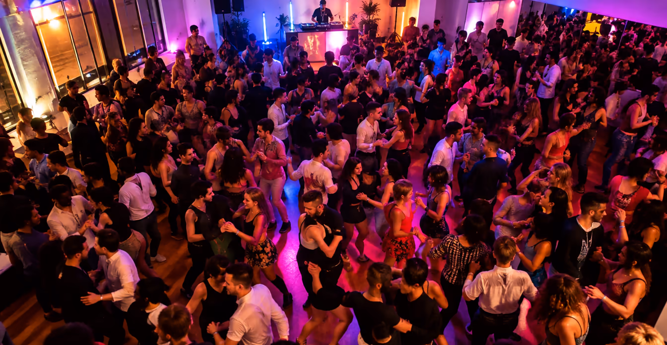 Soirée dansante bondée avec DJ et lumières colorées.